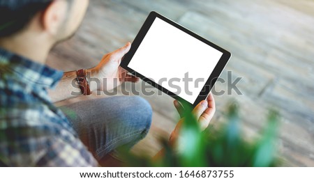 Mockup of a man holds tablet computer with isolated screen in his hands. View from above. Clipping path. Royalty-Free Stock Photo #1646873755