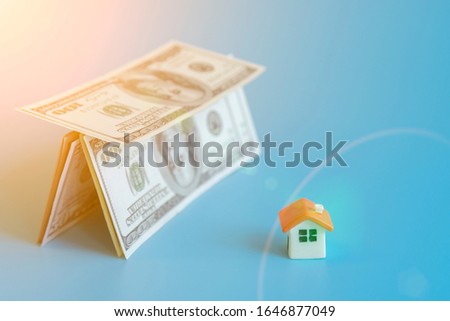 depicts saving for a house or flat manageable. Mortgage concept. house figurine and house made of dollars on a blue background. toned