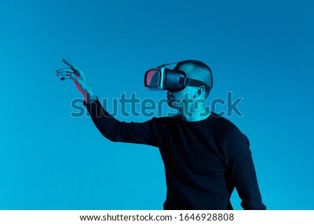 VR, AR, MR, XR-  Future technology. Neon. European man's in VR-glasses in neon on gradient background. Male portrait. Concept of human emotions, facial expression, modern gadgets and technologies. Loo
