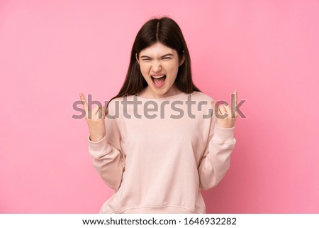 Young Ukrainian teenager girl over isolated pink background making rock gesture