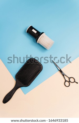 Flat lay composition with professional hairdresser tools on pastel color blue and beige background. Brush for brushing hair, comb for combing and scissors for cutting on a pastel background