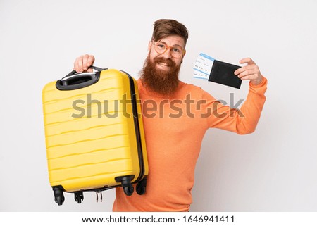 Redhead man with long beard over isolated white background in vacation with suitcase and passport