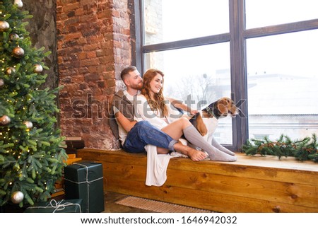 young beautiful couple is sitting at the window with two dogs in a loft apartment