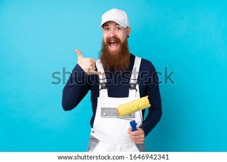 Painter man with long beard over isolated blue background making phone gesture