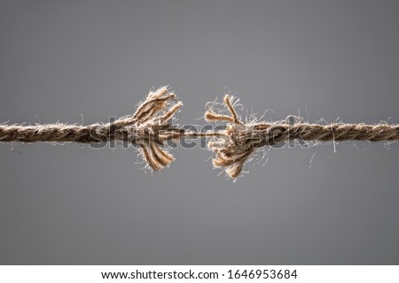 Frayed rope about to break concept for stress, problem, fragility or precarious business situation Royalty-Free Stock Photo #1646953684