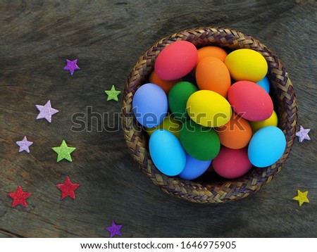 Top view colorful Easter eggs in the basket on wooden background with paper star.