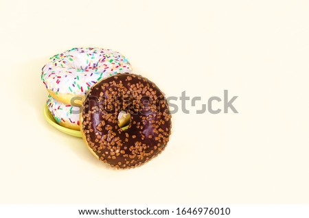 stack of donuts with white icing and a fallen chocolate doughnut on yellow background. trend in food. copy space