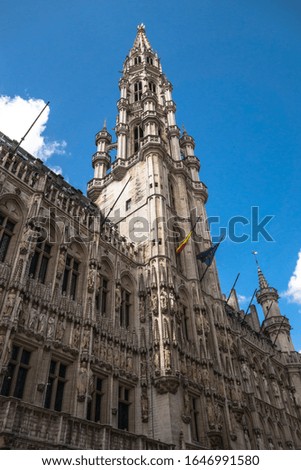 Brussels Town Hall tower with Belgian and European flag in front of blue sky. Royalty free stock photo.