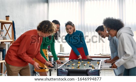Young and happy multicultural people in casual wear playing table soccer in the modern office. Office activities. Having fun together. Happy employees Royalty-Free Stock Photo #1646994877