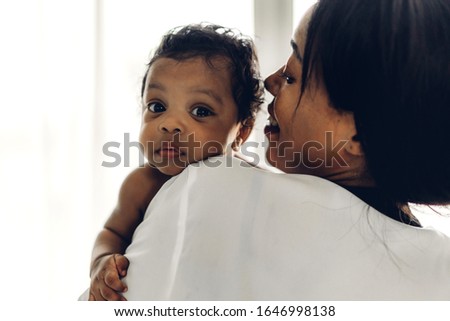 African american mother holding adorable little african american baby in her arms in bedroom.Love of black family concept