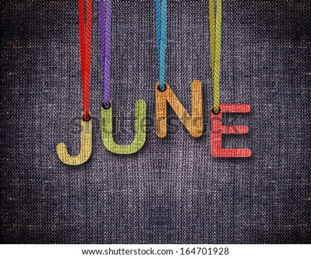 June letters hanging strings with blue sackcloth background.