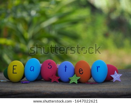 Colorful eggs write Easter words at horizontal row and paper star on the wood table nature background.
