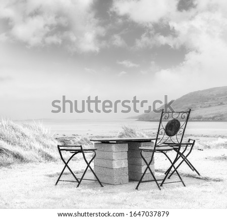 Beautiful white landscape with black chairs and concrete table on seashore. Black white.