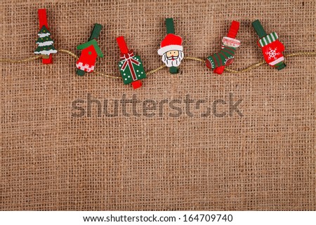 Little funny Christmas ornaments on golden thread, burlap background 