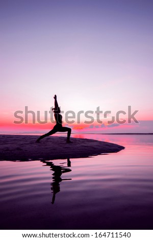Silhouette woman with yoga posture on the beach at sunset with reflection.