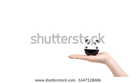 Hand with face cream in plastic panda container. Isolated on white background. Copy space, template.