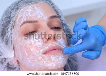 Cosmetologist is applying cream with anesthesia on patient's face, portrait closeup view. Preparing skin for biorevitalization procedure in cosmetology. Woman in beauty clinic with doctor beautician.