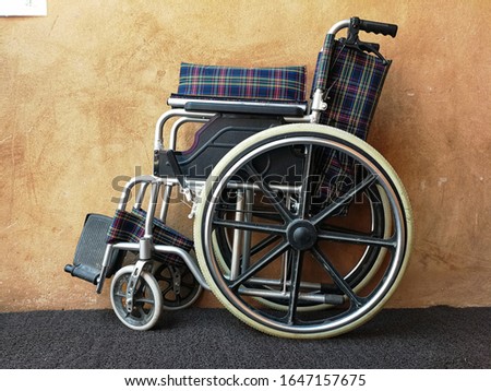 Empty wheelchair near cement wall indoors. Space for text