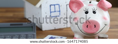 Calculator with piggy bank against home background closeup. Mortage credit concept