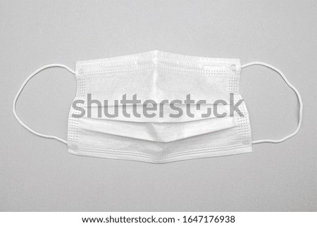 Surgical mask with rubber earband. A typical three-layer surgical mask covering the nose and mouth.