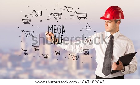Handsome businessman with helmet drawing MEGA SALE inscription, contruction sale concept