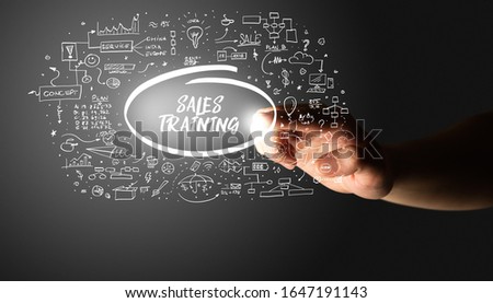 Hand touching SALES TRAINING inscription, hand drawn icons around, business plan concept