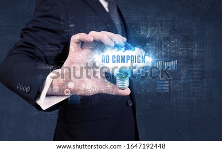 Businessman holding a light bulb with AD CAMPAIGN inscription, new business concept