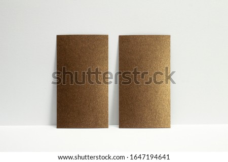 2 blank bronze business cards locked on white wall, 3.5 x 2 inches size as template for design presentation, showcase etc.