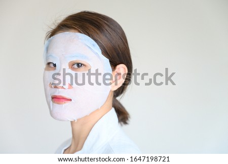 Portrait of young woman applying facial mask for enhance her skin and looking to camera. Facial mask is a creamy or thick pasted mask applied to clean or smoothen the face.