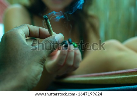 A person putting a lit up cigarette into the woman's hands