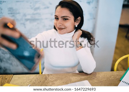 Caucasian woman 20s making selfie pictures via cellphone application connecting to 4g wireless for video blogging, pretty female influencer shooting vlog content while networking web internet
