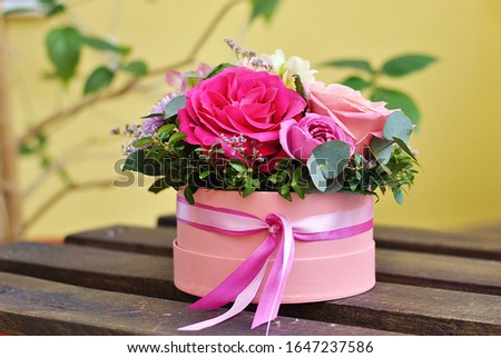 Beautiful round pink box with floral composition with roses of different color. Flowers lush bouquet picture close up view. Holiday, birthday, florist shop business or beauty concept. Romantic flower