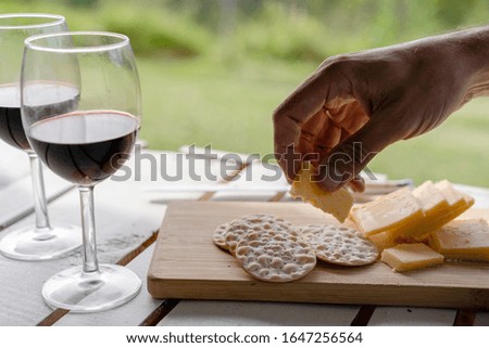 people having brunch, eating cheese and crackers outside and also enjoying a glass of red wine