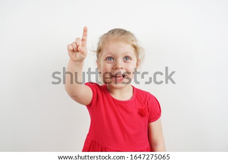 Little girl in a pink dress shows a finger. Concept for advertising. The child shows to pay attention to the subject or words. Place for text. Cute, beautiful, smiling chil Royalty-Free Stock Photo #1647275065