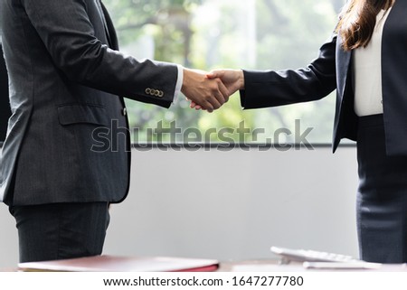 Male and female business people shaking hands in office