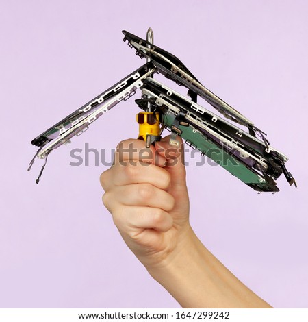 Hand holding broke phone screens on screwdriver reapir service on purple background.