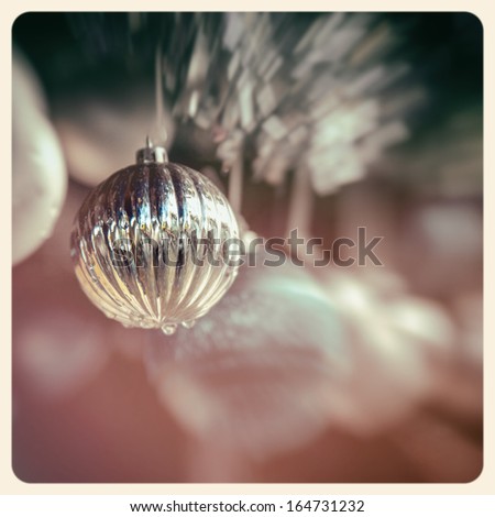 Detail of christmas baubles with tinsel. Selective focus and bokeh background. Cross-processed with pastel shades, to create a retro instant photo effect.
