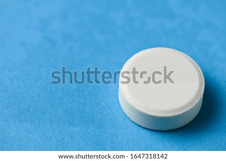 One big white pill on blue background, macro photo, health care and medicine concept, blank space for text