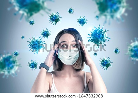 Scared young woman in protective mask standing near grey wall with blurry blue viruses around her. Concept of coronavirus flu panic Royalty-Free Stock Photo #1647332908