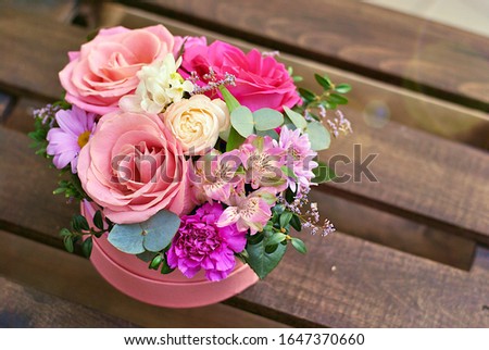 Beautiful round pink box with floral composition with roses of different color. Flowers lush bouquet picture close up view. Holiday, birthday, florist shop business or beauty concept. Romantic flower