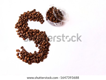 Roasted brown coffee beans in a transparent cup on a white background. Letter S made from coffee beans. Good Isolated on white background. High quality photo. Studio shot, copy space for your text