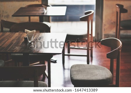  wooden tables and wooden chairs near the window glass in cafe with sunlight