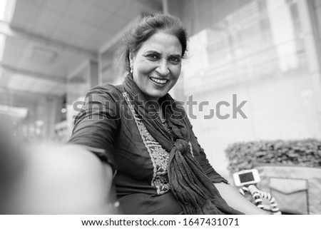 Happy mature beautiful Indian woman exploring the city