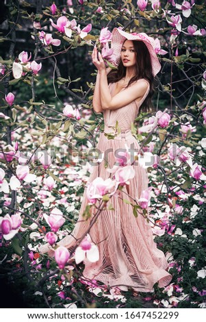 a full-length girl holding a magnolia tree in spring