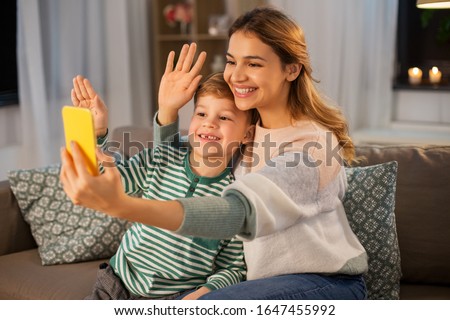 family, technology and people concept - happy smiling mother and little son with smartphone having video call and waving hands at home