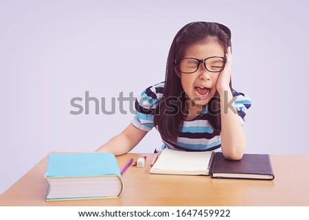 Bored and tired asian student girl doing homework, isolated on grey background