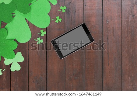 holidays and technology concept - tablet pc computer and st patricks day decorations made of paper on wooden background