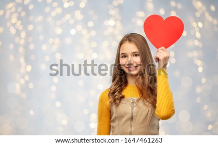 valentine's day, love and people concept - smiling young teenage girl with red heart over festive lights background