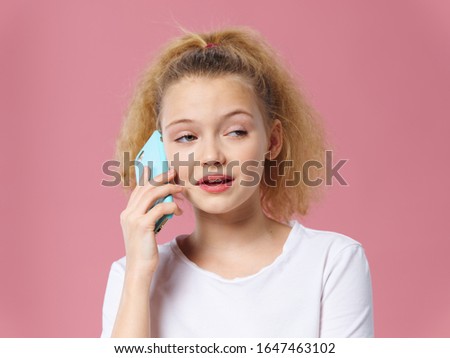 Beautiful little girl talking on the phone studio lifestyle pink background