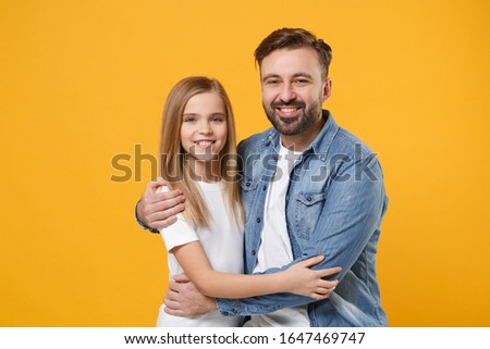 Smiling bearded man in casual clothes hugging with cute child baby girl. Father, little kid daughter isolated on yellow orange background studio portrait. Love family day parenthood childhood concept